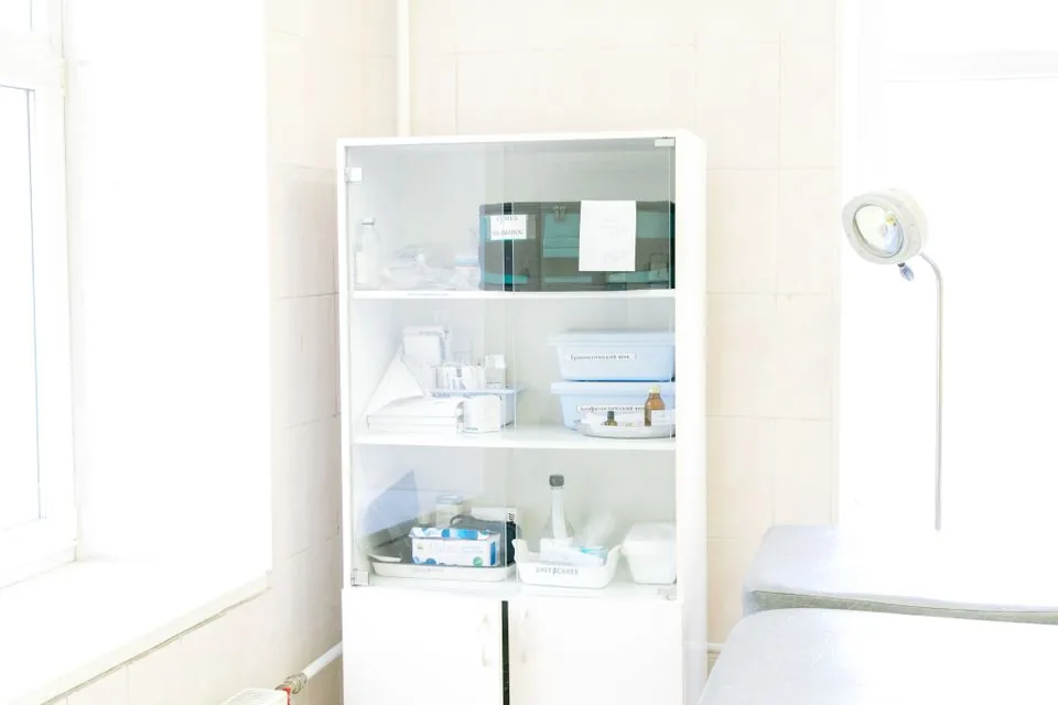Heller Behandlungsraum mit Liege und medizinischem Schrank